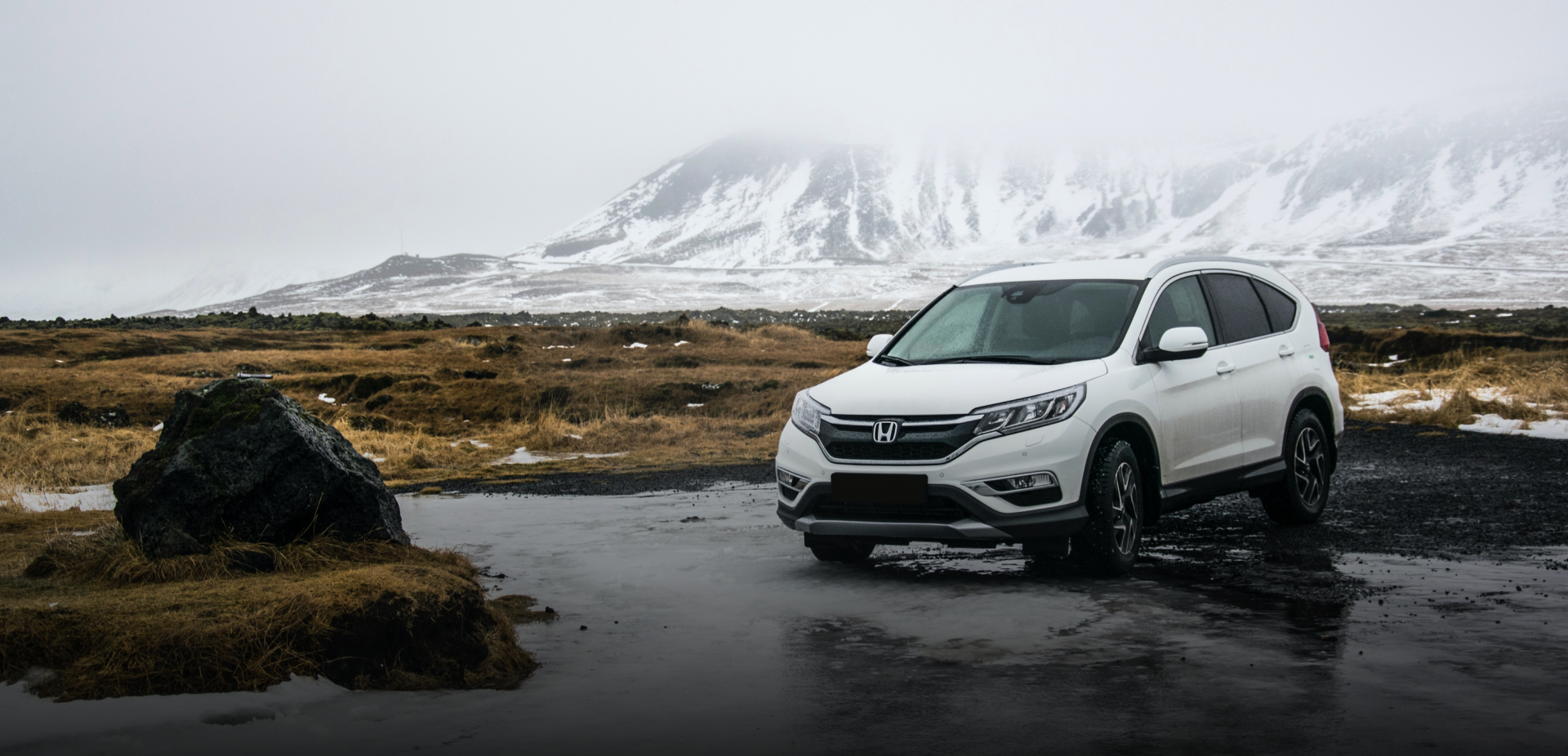 Vit Honda i kyligt landskap med snötäckta berg bakom